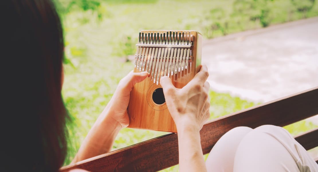 A woman seen from behind playing a wooden kalimba