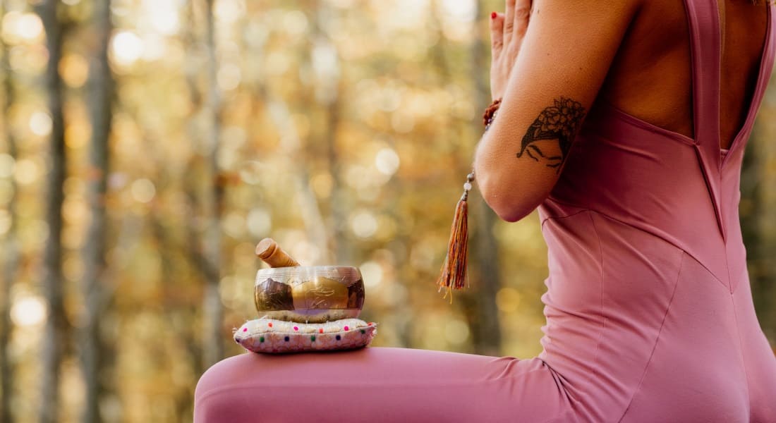 A woman dressed in pink with a Tibetan bowl on her thigh