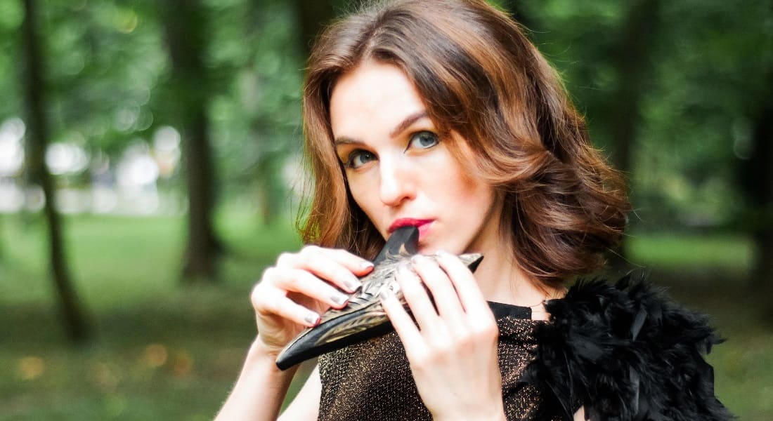 A woman in the forest blowing into an ocarina