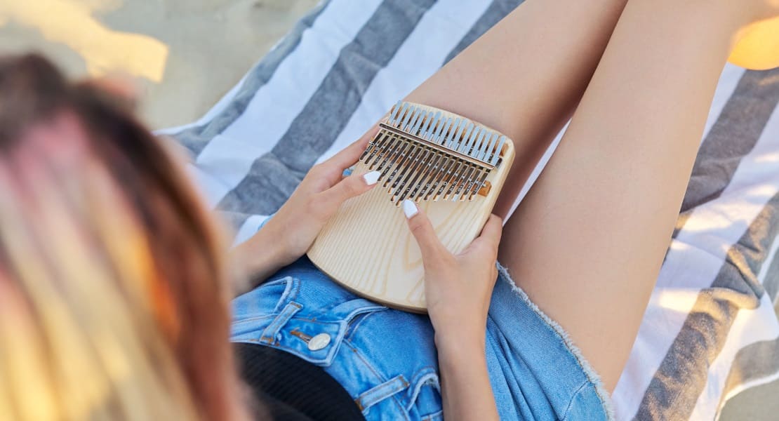 A woman lying down playing a wooden kalimba
