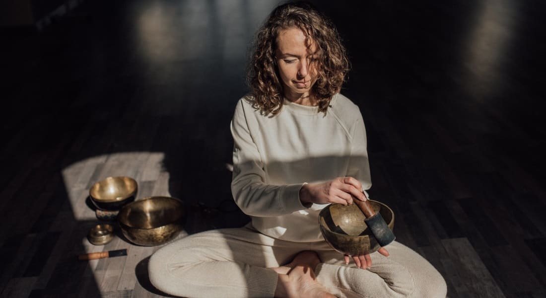 A woman meditating on the floor with Tibetan singing bowls