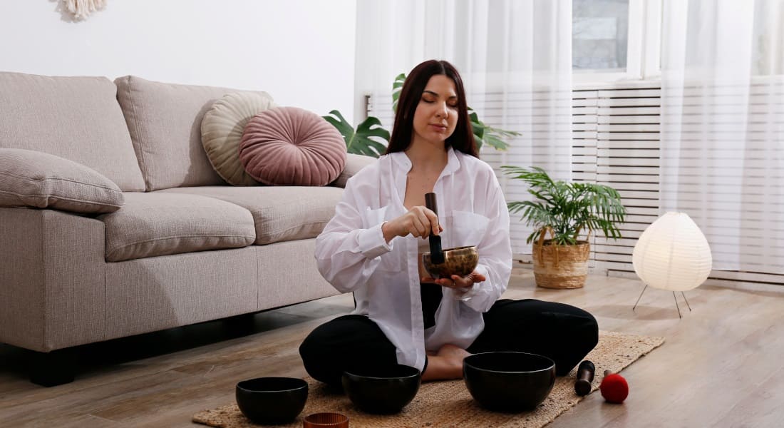 A woman meditating with 4 metal singing bowls