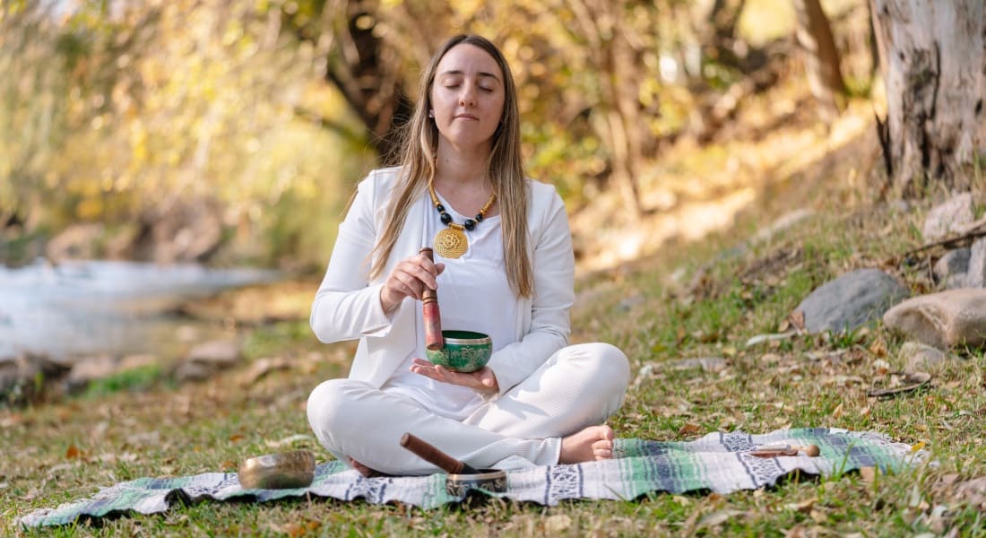 A woman meditating with a green Tibetan singing bowl