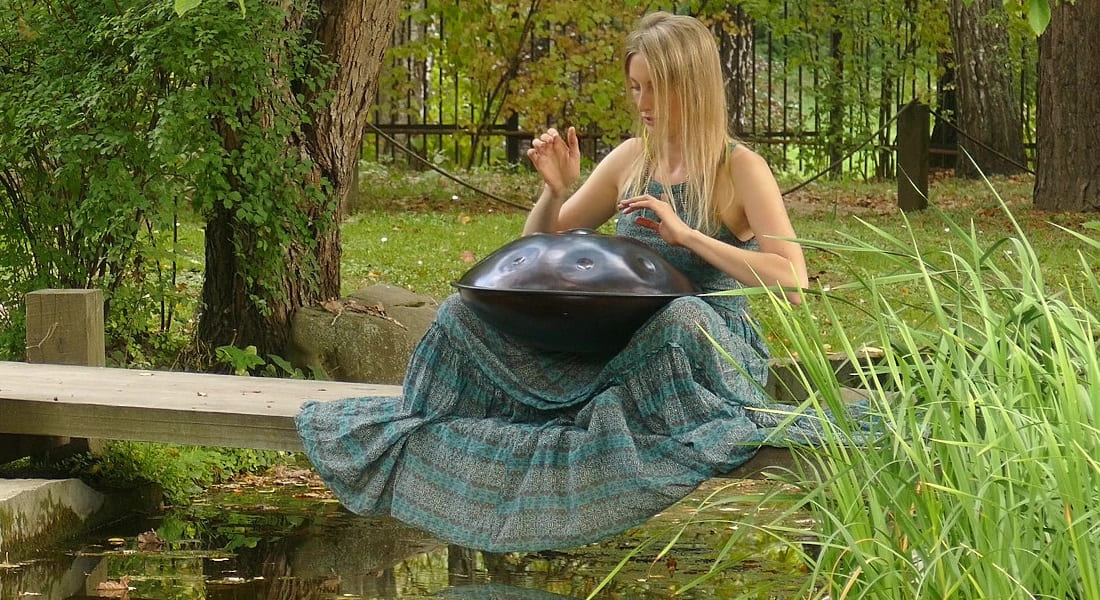 A woman playing handpan in a park