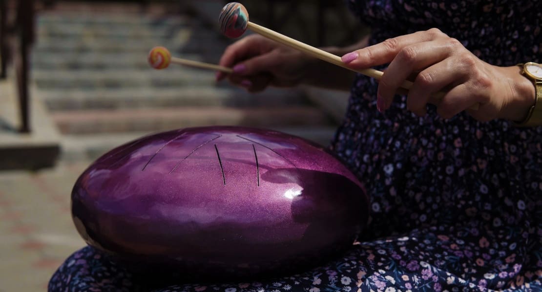 A woman playing a purple tongue drum