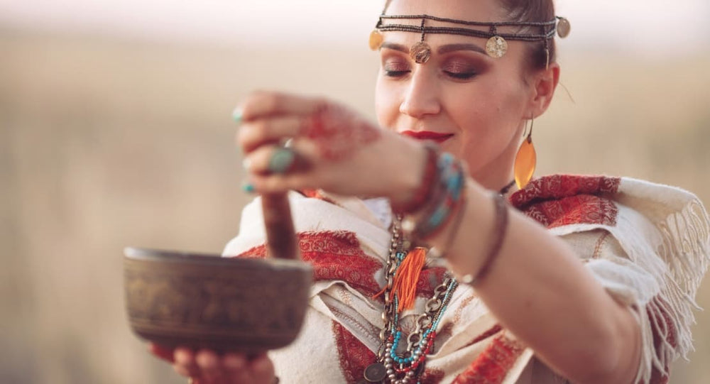 A woman playing a Tibetan singing bowl in traditional attire
