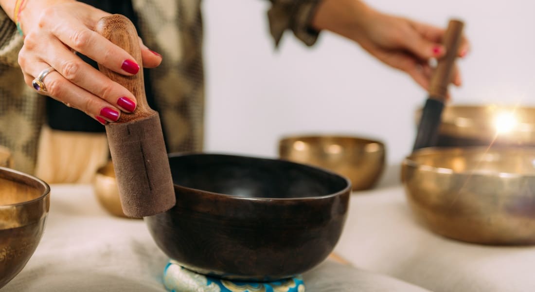 A woman practicing sound therapy with Tibetan singing bowls