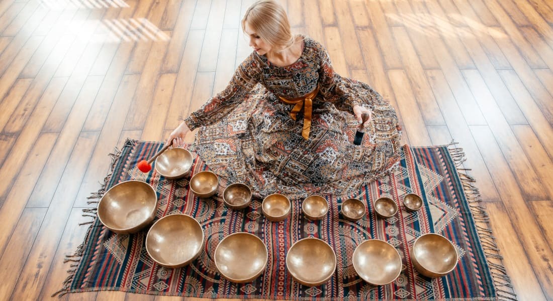 A woman sitting in front of 15 metal singing bowls