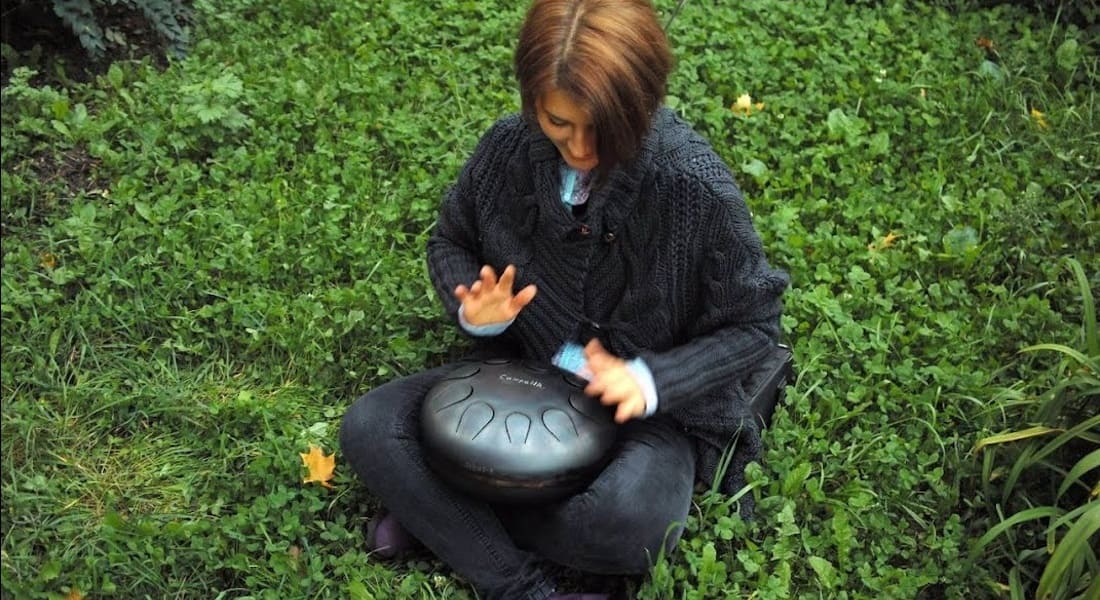 A woman sitting in the grass with a tongue drum