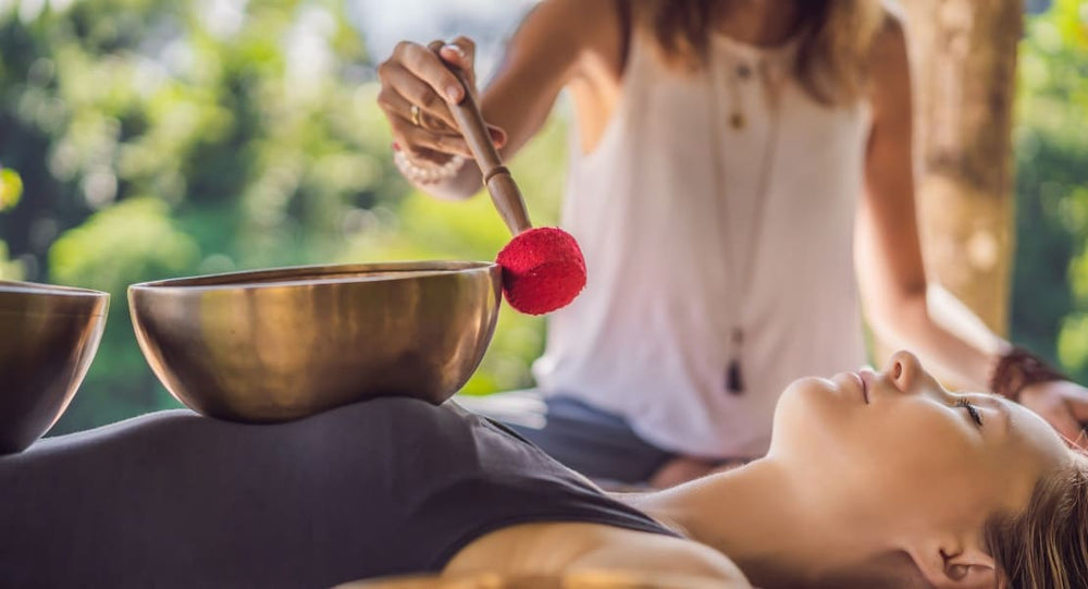 A woman performing a sound massage with Tibetan singing bowls