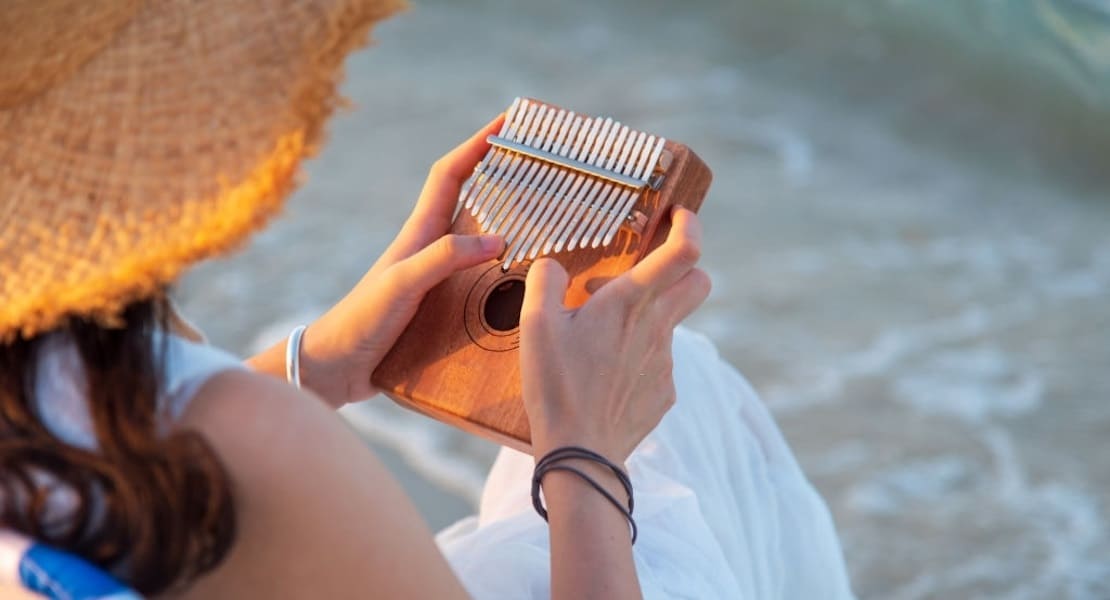 A woman wearing a straw hat playing the kalimba