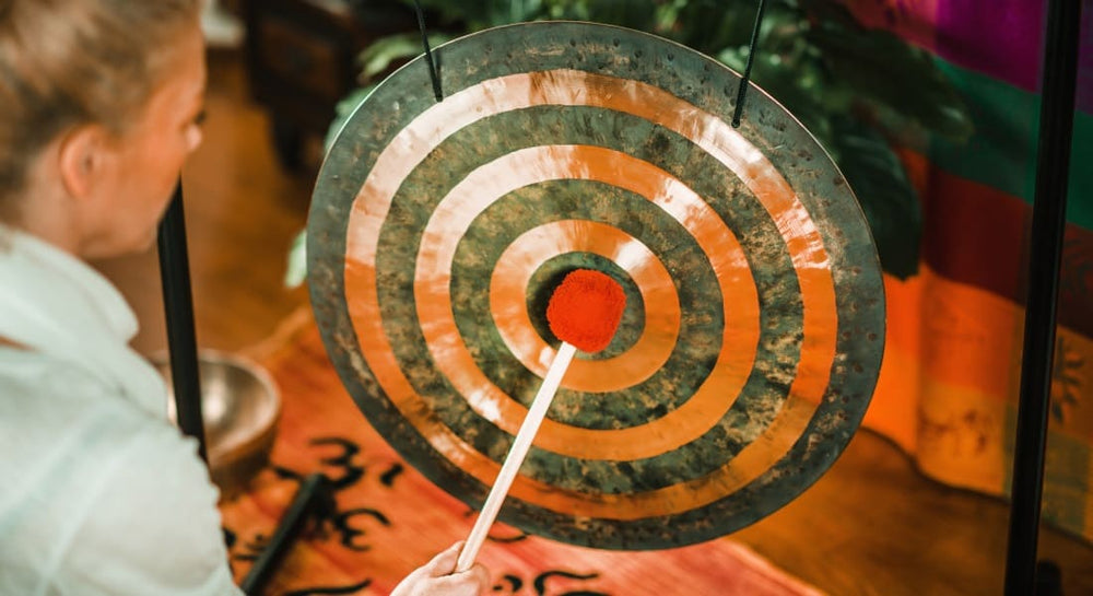 A woman striking a gong with a mallet