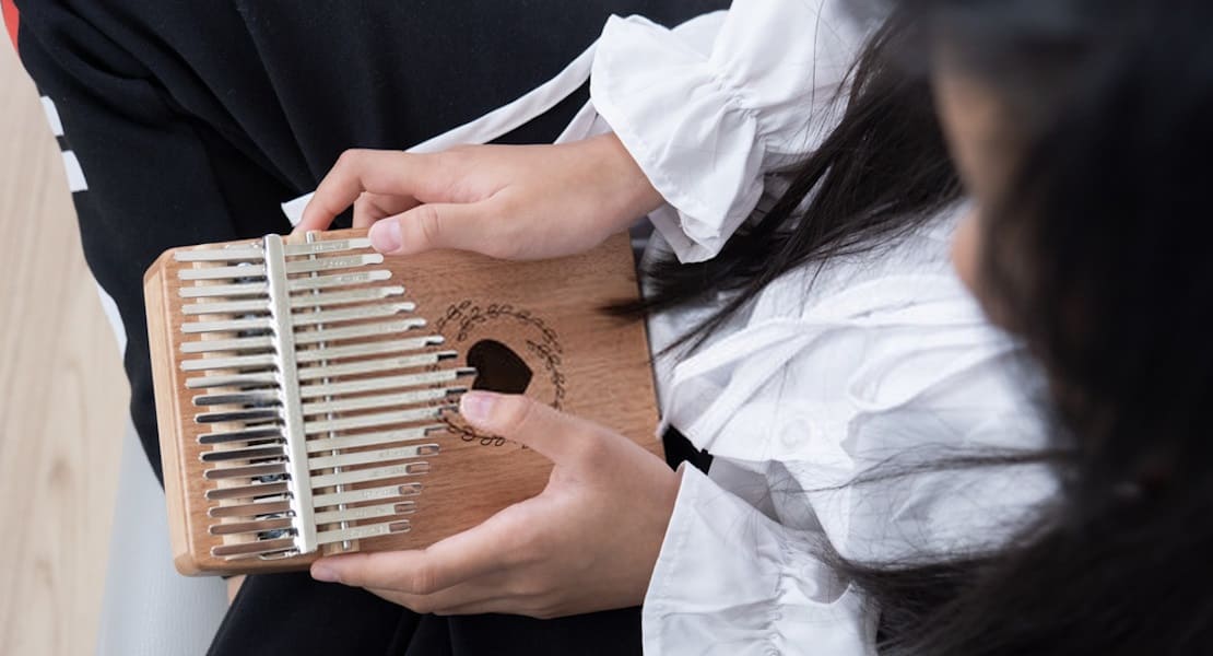 A top-down view of a woman sitting cross-legged playing a kalimba