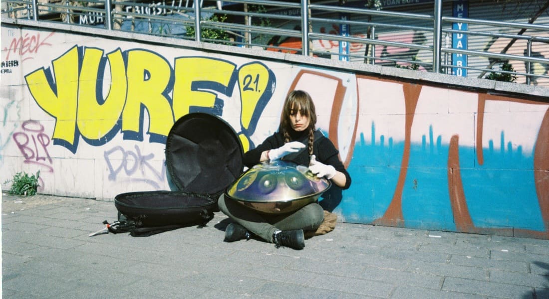 A woman traveling and playing a handpan in an airport