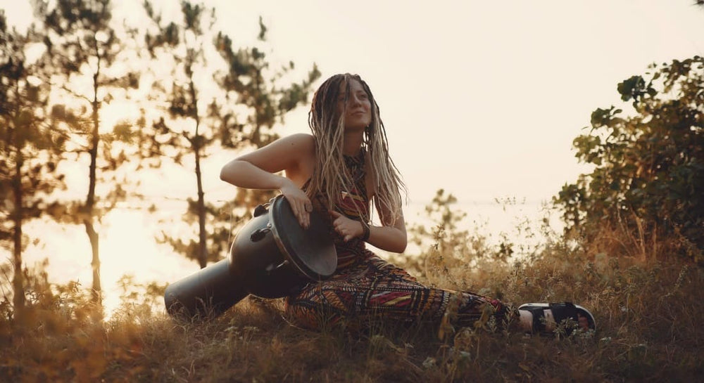 A woman with dreadlocks playing a drum