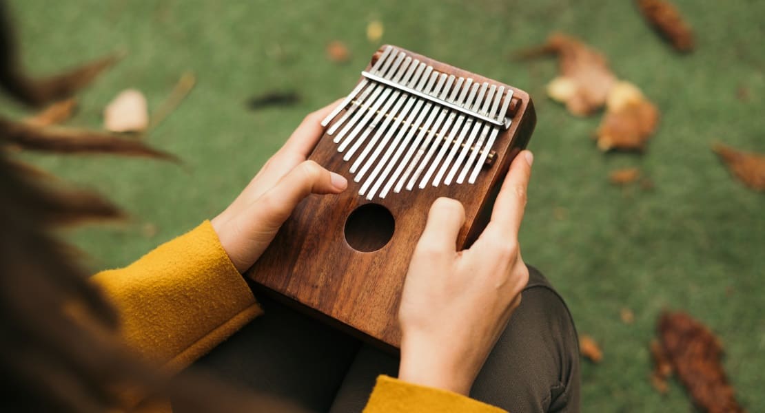 A woman in yellow sleeves playing the kalimba