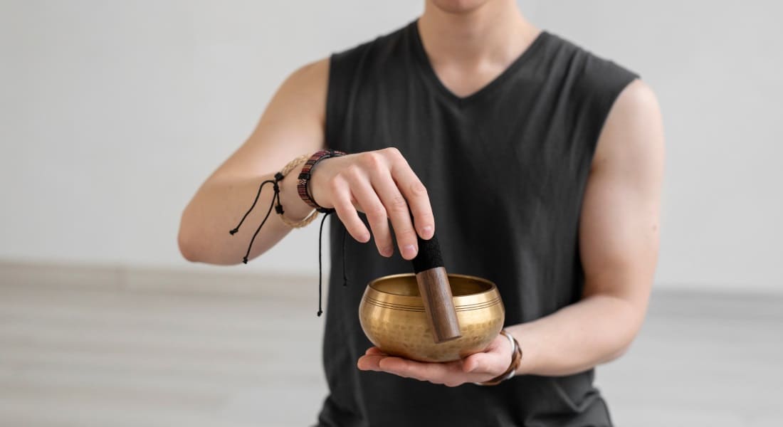 A young man meditating with a Tibetan singing bowl